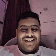 a man with a mustache and a white shirt is smiling with his eyes closed