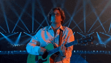 a man wearing glasses is playing a guitar on a stage