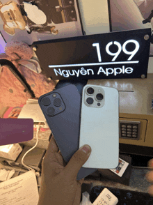 a person holding a phone in front of a sign that says 199 nguyên apple
