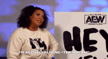 a woman is standing in front of a sign that says aew wrestling