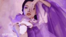 a woman in a purple dress covering her face with her hand .
