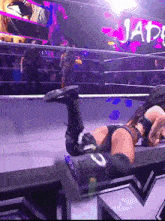 a woman is laying on the ground in a wrestling ring with a sign that says jat