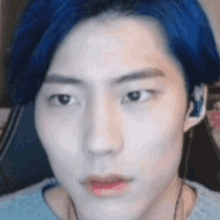 a close up of a man 's face with blue hair and headphones .