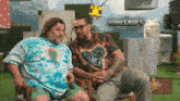 two men sit next to each other in front of a minecraft movie poster