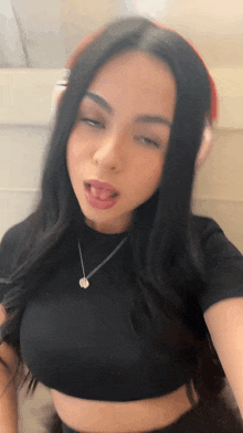 a woman wearing headphones and a black crop top is sticking out her tongue .