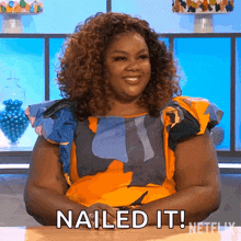 a woman with curly hair is sitting at a table with the words nailed it next to her