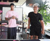 a man in a pink shirt and a man in a black shirt are standing next to each other