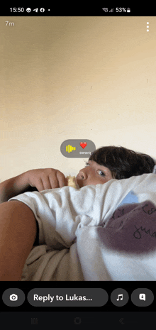a phone screen shows a person laying on a bed with a reply to lukas button