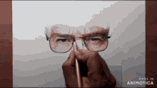 a person is drawing a man 's face with glasses and a pencil .