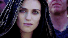 a woman with a hood on her head is looking at the camera