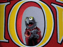 a muppet is playing a trumpet in front of the letter o.