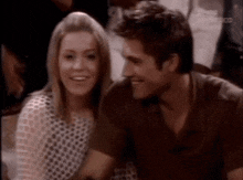 a man and a woman are sitting next to each other and smiling for the camera .