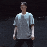 a young man in a grey t-shirt and black pants is standing on a stage .