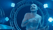 a shirtless man playing drums in front of a circle of lights