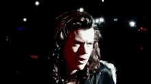 harry styles is smiling in a black and red photo .