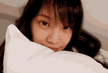 a close up of a woman 's face with a white pillow covering her face