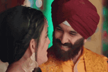 a man in a turban looks at a woman in a yellow dress