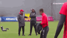 a man in a red shirt is dancing on a soccer field while a group of men watch .