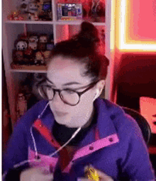 a woman wearing glasses and headphones is sitting in front of a shelf with toys .