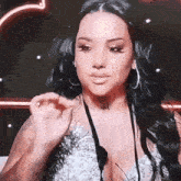 a woman with long black hair is wearing a plunging neckline and hoop earrings .