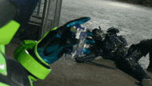 a person wearing a green and blue glove is holding a purple object