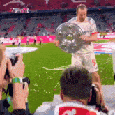 a soccer player holding a trophy on a field