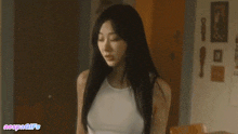 a woman in a white tank top is standing in a room