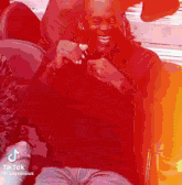 a man in a red shirt is sitting in a chair and smiling while holding a microphone .