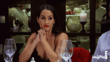 a woman sits at a table with wine glasses and a gif that says imgplay