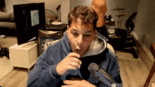 a man in a blue hoodie is eating something in front of a microphone that says chelsea on it
