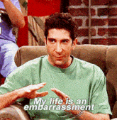 a man in a green shirt says " my life is an embarrassment " while sitting on a couch