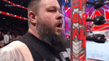 a man with a beard is standing in front of a wrestling ring that says raw
