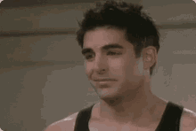 a close up of a man wearing a black tank top and smiling .