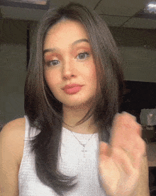 a woman wearing a white top and a necklace with a cross on it
