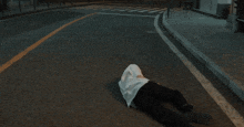 a person laying on the side of a road with their head in the ground