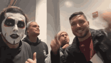 a group of men are posing for a picture with one wearing a clown face paint