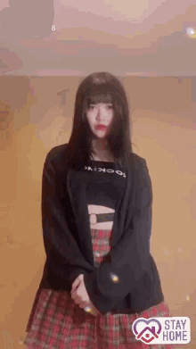 a girl wearing a plaid skirt and a black sweater with the words stay home on the bottom