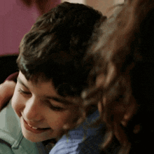 a boy and a girl are hugging each other and the boy is smiling