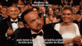 a man in a tuxedo and bow tie is sitting in front of a crowd of people with the caption members da woodlands