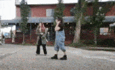 two women are standing on the sidewalk in front of a building