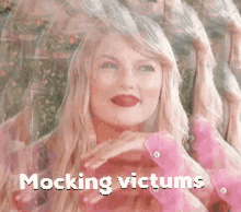 a woman in a pink shirt is smiling with the words mocking victims written above her .