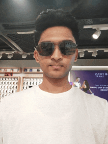a man wearing sunglasses is standing in front of a sign that says ' iatiit ' on it