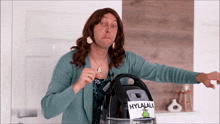 a woman in a wig is standing next to a vacuum cleaner that has a label on it that says hylala