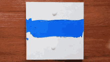a person is painting a blue stripe on a white surface with a brush .
