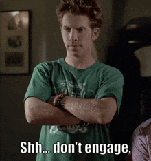 a man in a green shirt with his arms crossed says " shh... don 't engage "