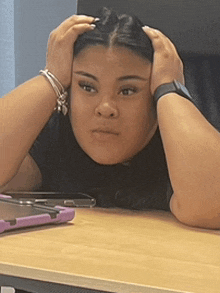 a woman is sitting at a desk holding her head