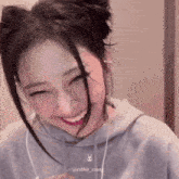 a woman wearing headphones and a rabbit necklace is smiling