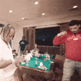 two men standing in front of a pool table one wearing a red hoodie that says beevc