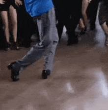 a man in a blue shirt is dancing in front of a crowd of people .