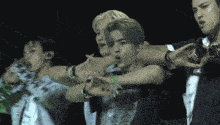 a group of men are dancing in a dark room with a green light behind them
